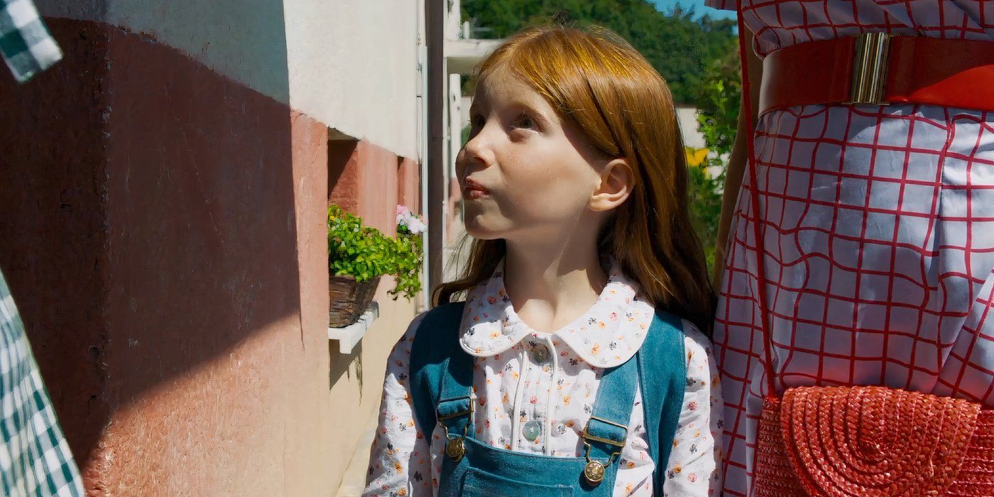 a little girl with red hair looking up at two people out of frame