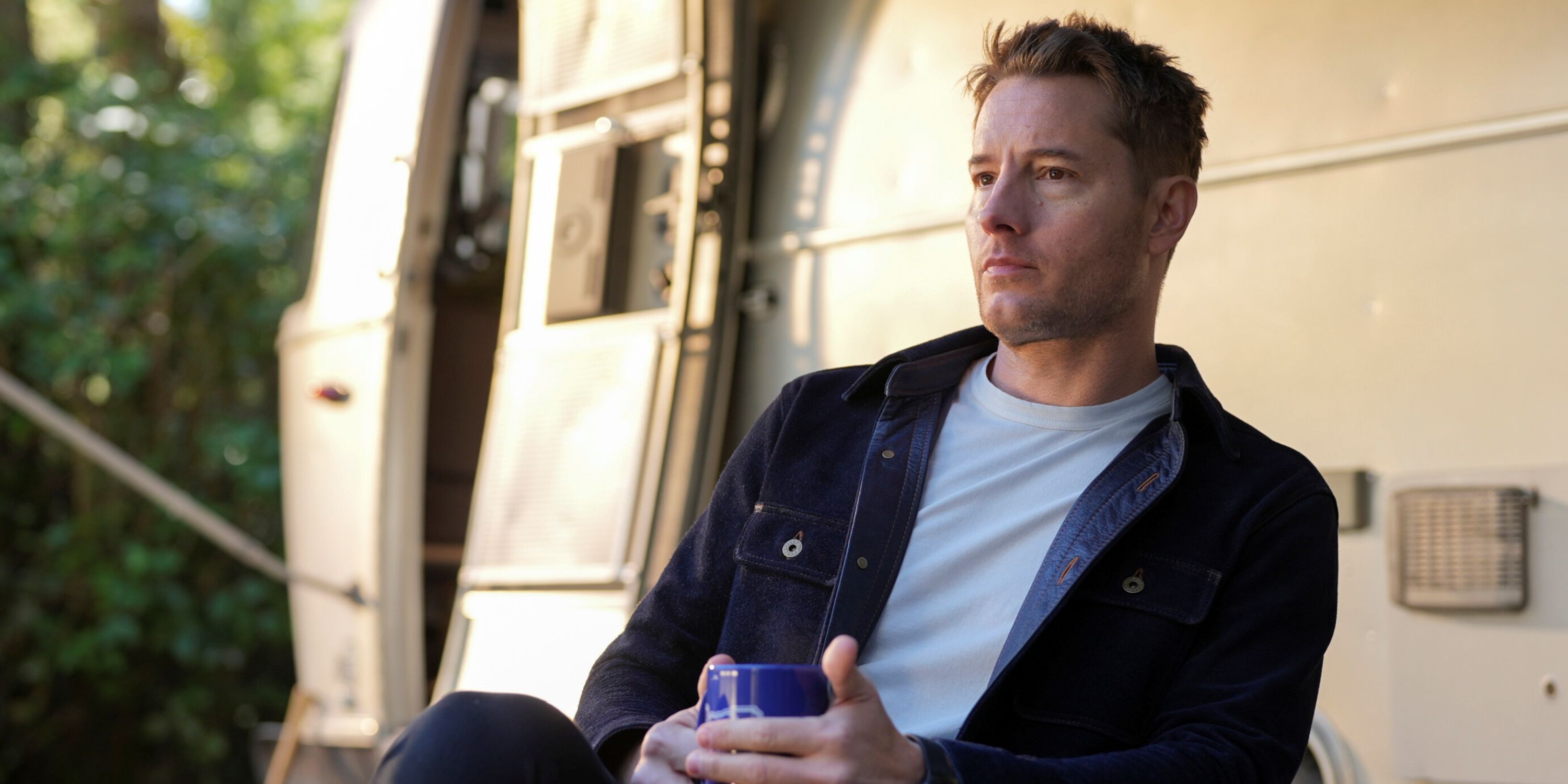 Justin Hartley as Colter Shaw sitting outside of his trailer in the daylight on the CBS series Tracker