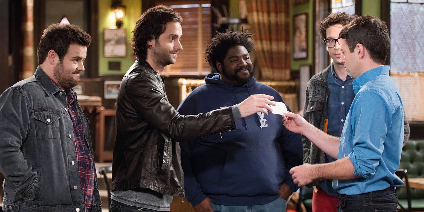 A group of men clinking glasses in a bar in a scene from the show Undateable.