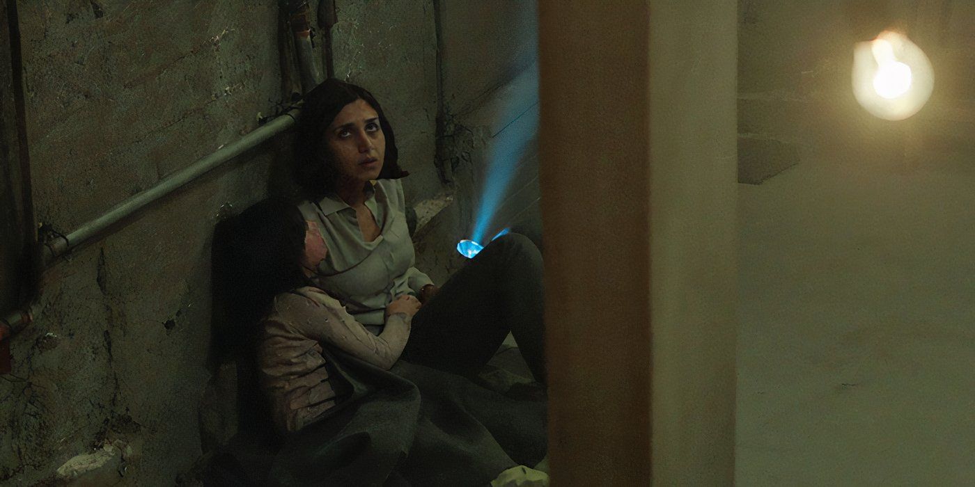 Shideh (Narges Rashidi) and Dorsa (Avin Manshadi) sit huddled against the wall. Shideh shines a flashlight at the ceiling