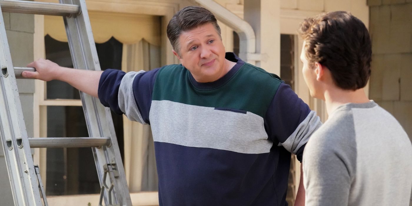 Lance Barber as George Sr. leaning on a ladder while talking to Montana Jordan as Georgie in Young Sheldon Season 7. 