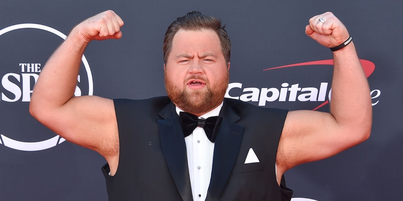 Paul Walter Hauser flexes his muscles in a short sleeve tux 