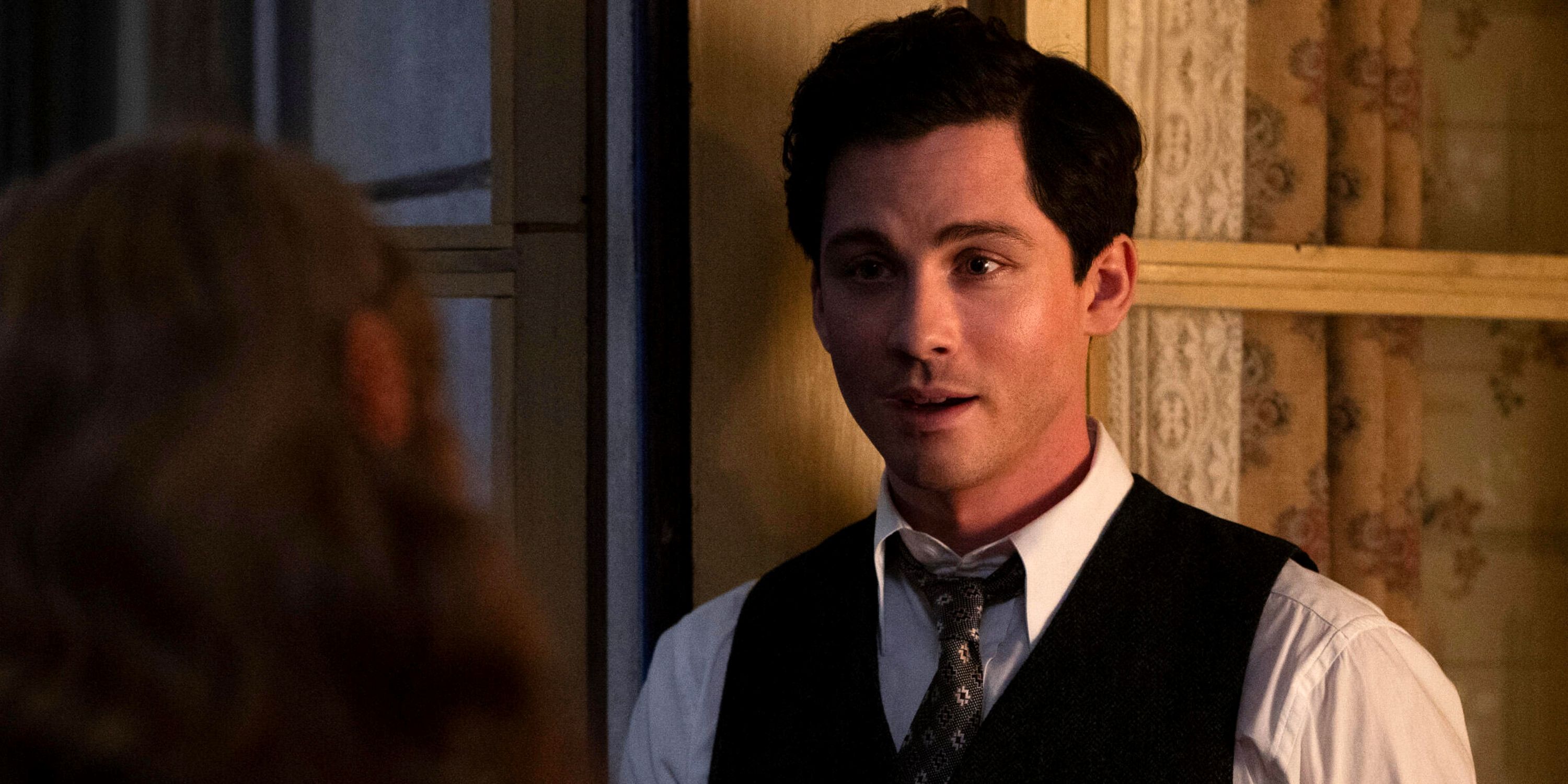 Logan Lerman as Addy Kurc in a suit and tie leaning against a wall in Episode 1 of We Were the Lucky Ones