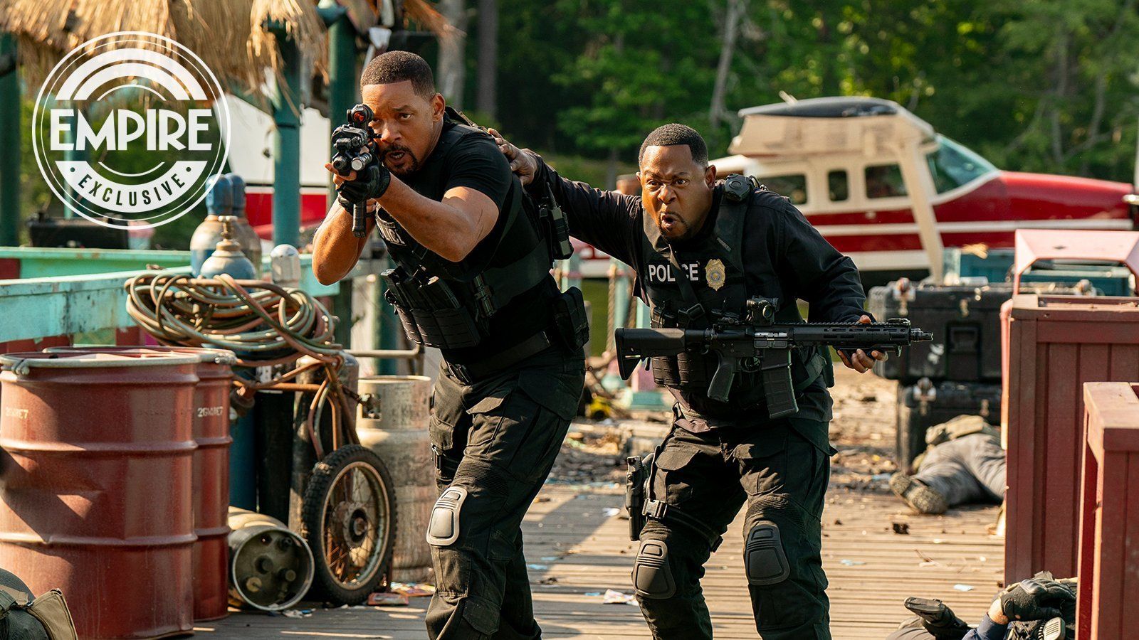 Martin Lawrence with his hand on Will Smith's shoulder as the two hold guns and head into battle