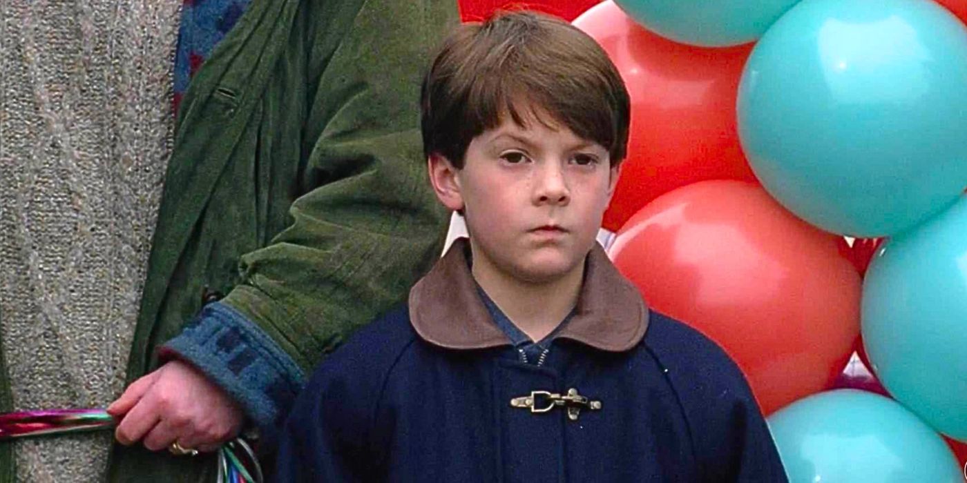 Young boy possessed by evil poltergeist stares blankly as he stands next to bundle of red and blue helium balloons from episode The Calusari in The X-Files