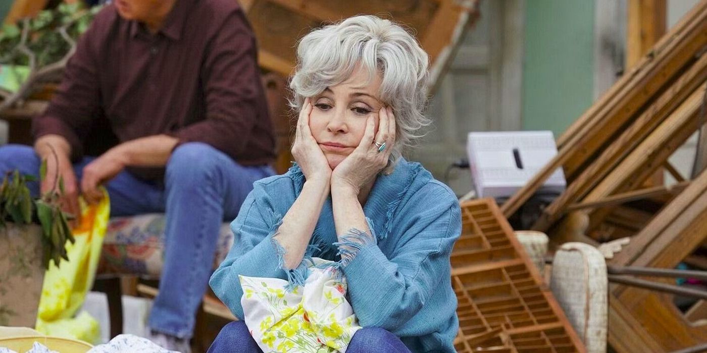 Connie from Young Sheldon sitting outside her house that has been blown apart by a tornado with her hands on her cheeks, Dale in the background.