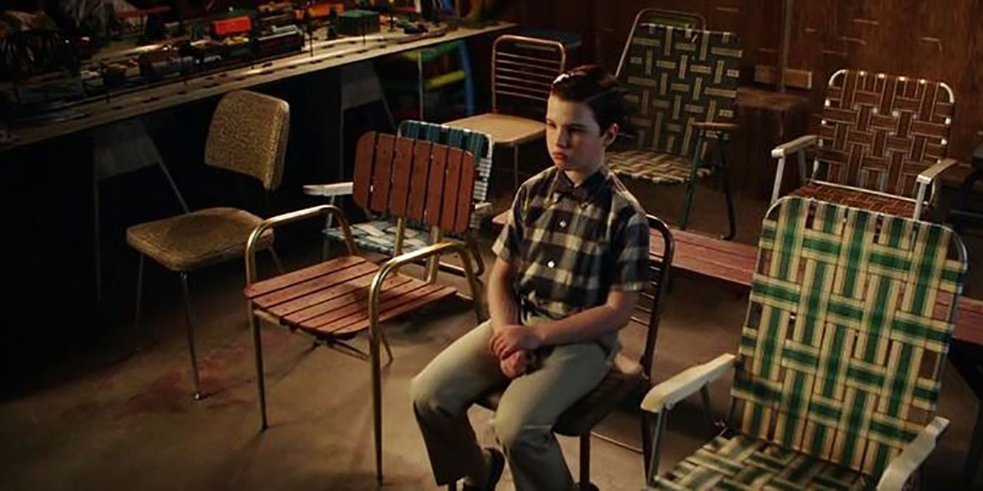 Sheldon from Young Sheldon sitting in his garage by himself, surrounded by empty chairs.