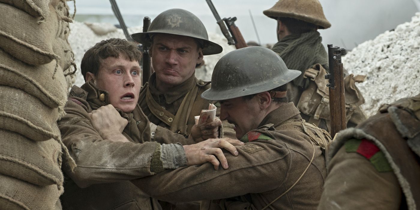 George MacKay as Lance Corporal William "Will" Schofield, looking stunned and being held back by other soldiers in a trench in 1917