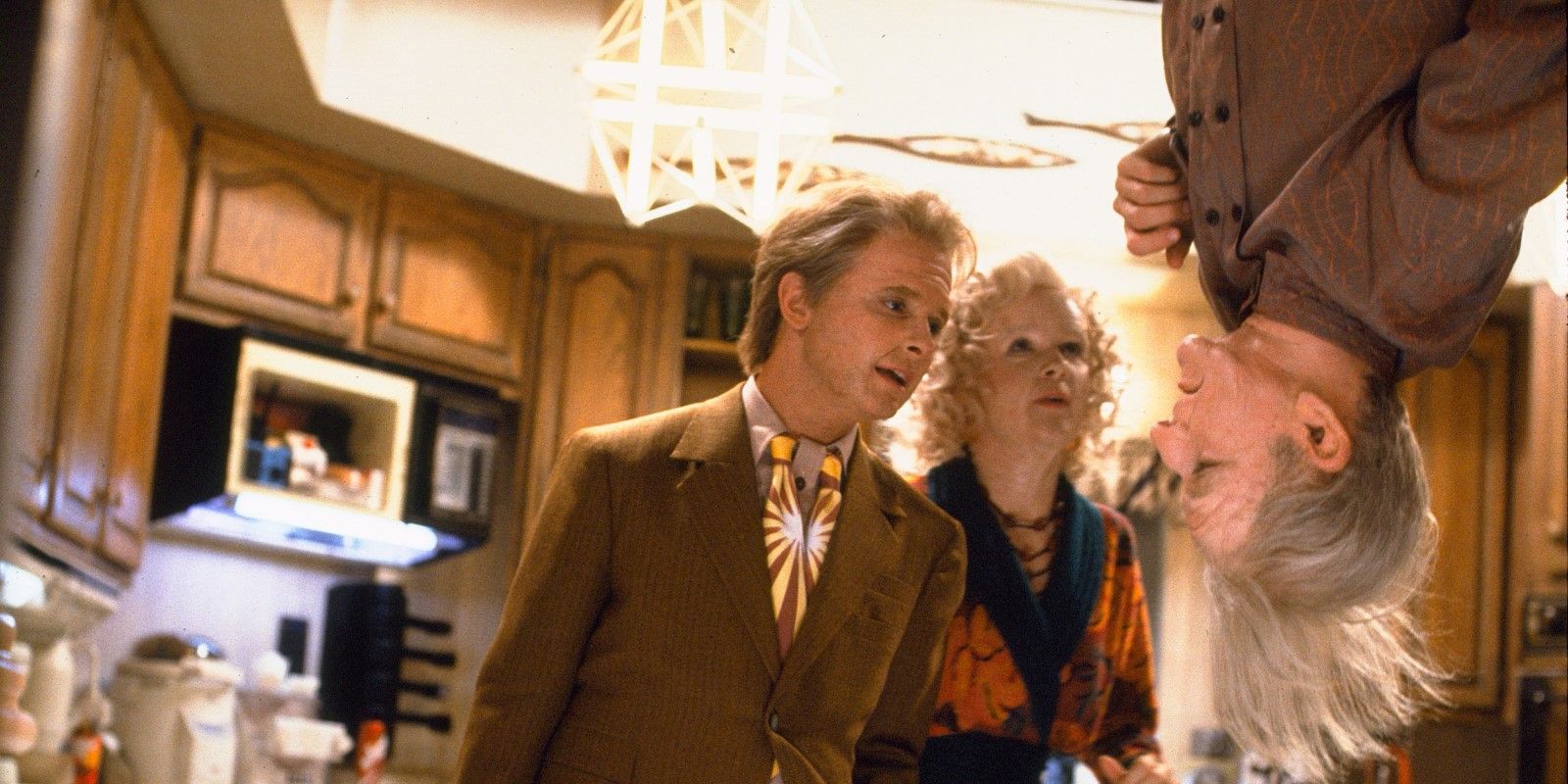 George McFly (Jeffrey Weissman) hangs upside down as Marty (Michael J. Fox) and Lorraine (Lea Thompson) stand beside him in 'Back to the Future Part II'