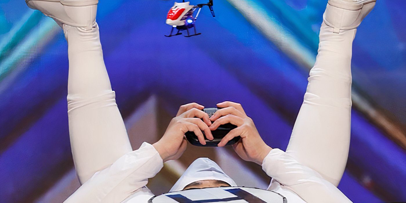 Kozo from America's Got Talent with his legs in the air navigating a drone to a paddle on his derrier.