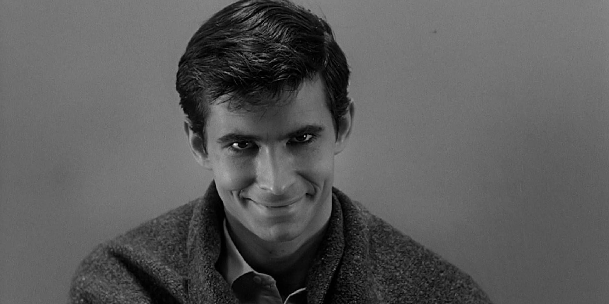 Anthony Perkins como Norman em Psicopata parecendo sinistro enquanto sorri.