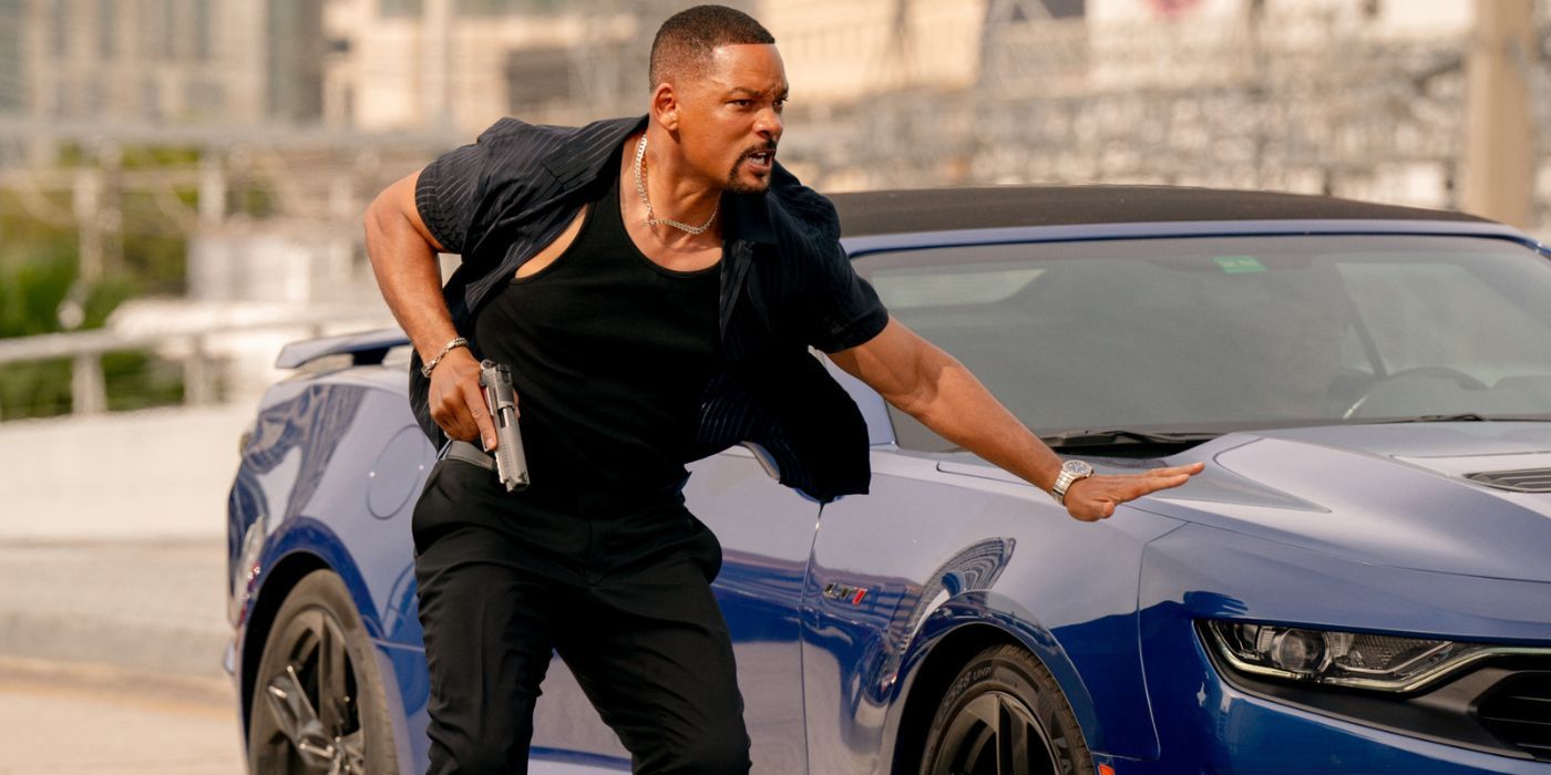 Will Smith holding his pistol with his palm on a blue car.