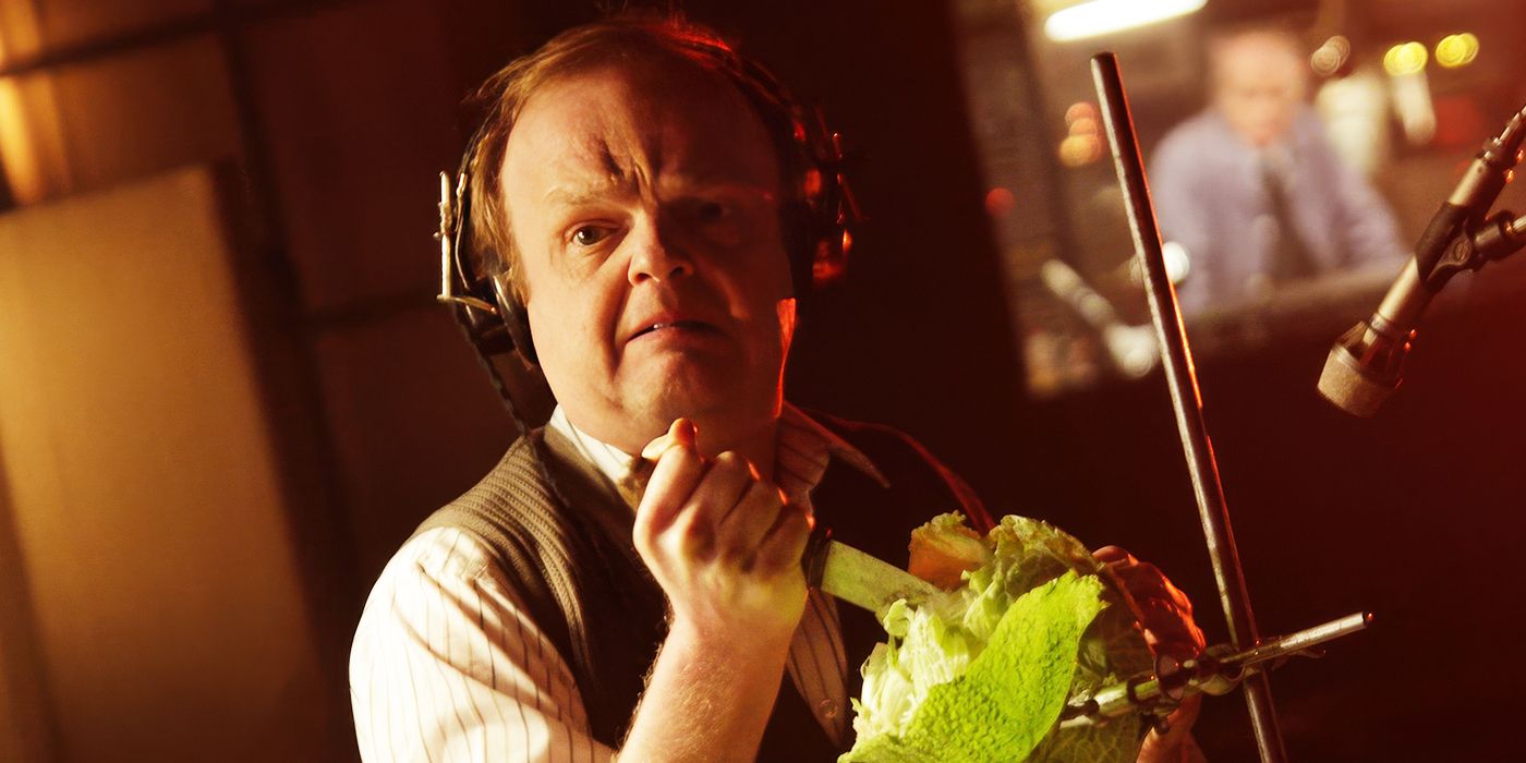 A man wearing headphones stabbing a lettuce while looking scared in Barberian Sound Studio