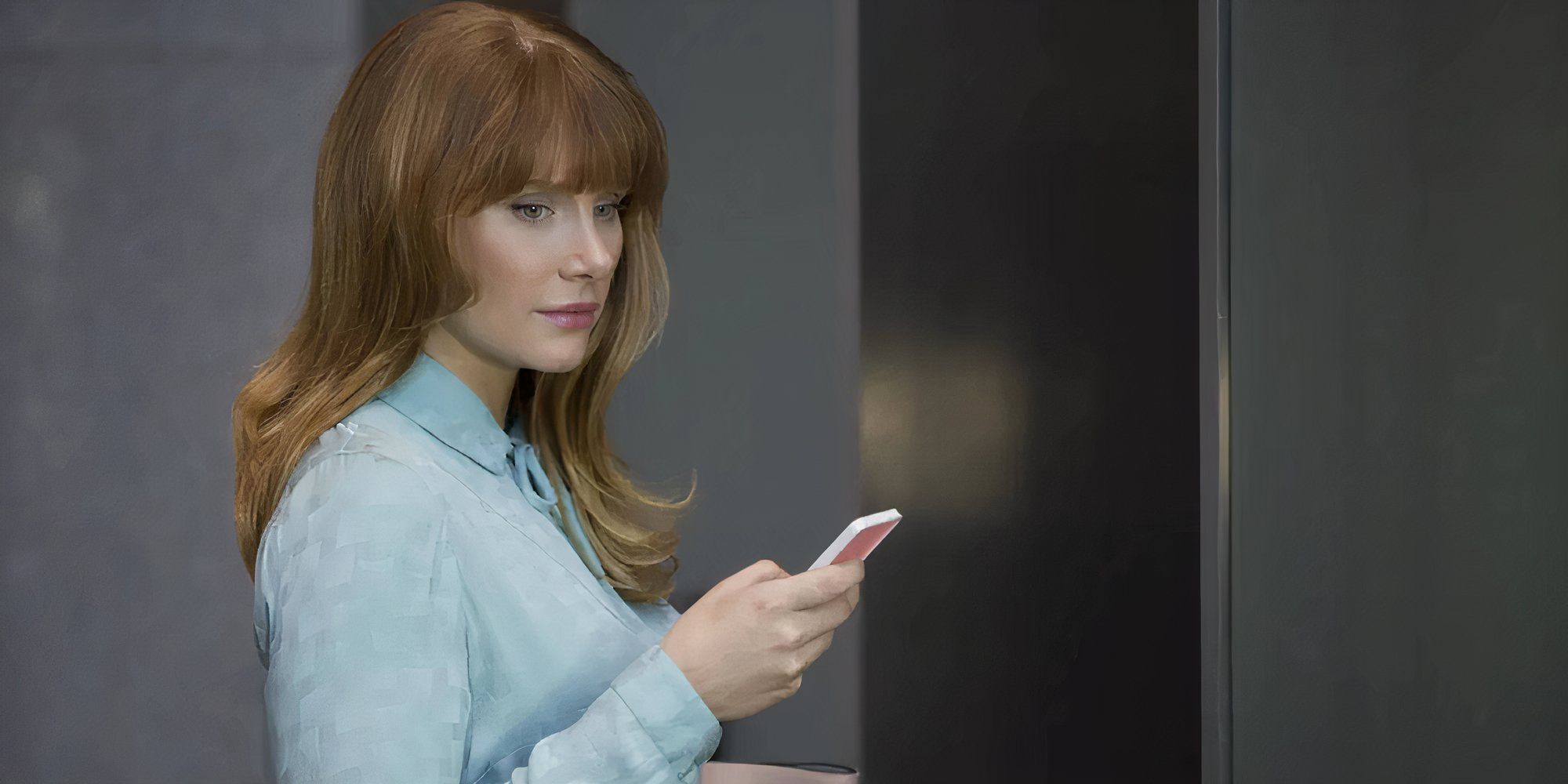 Bryce Dallas Howard as Lacie in Black Mirror Nosedive holding her phone but gazing into the void.