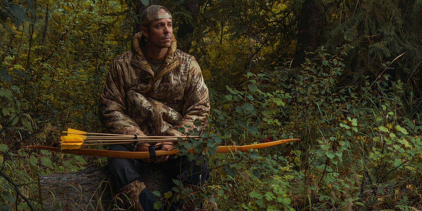 Sitting on a downed tree, a man dressed in camo holds a bow and set of arrows