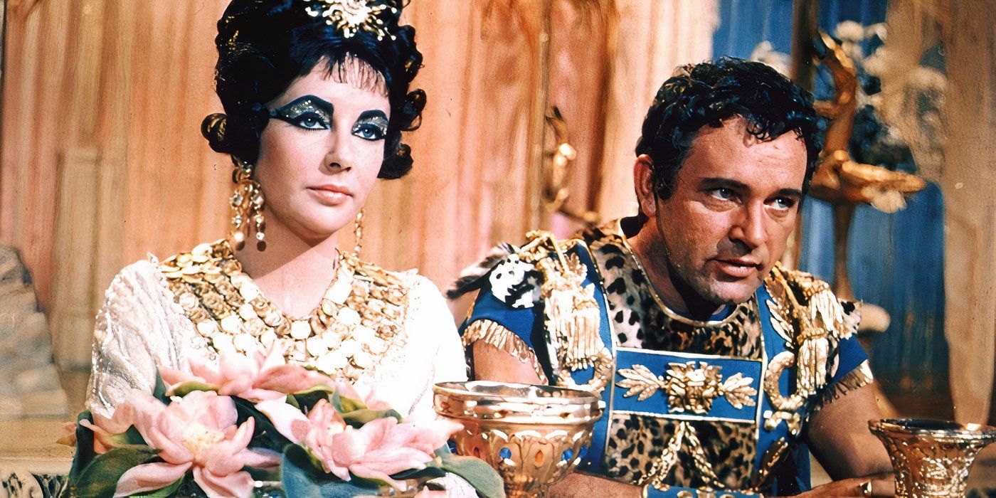 Elizabeth Taylor as Cleopatra (left) and Rex Harrison as Caesar (right) sitting at a table with goblets