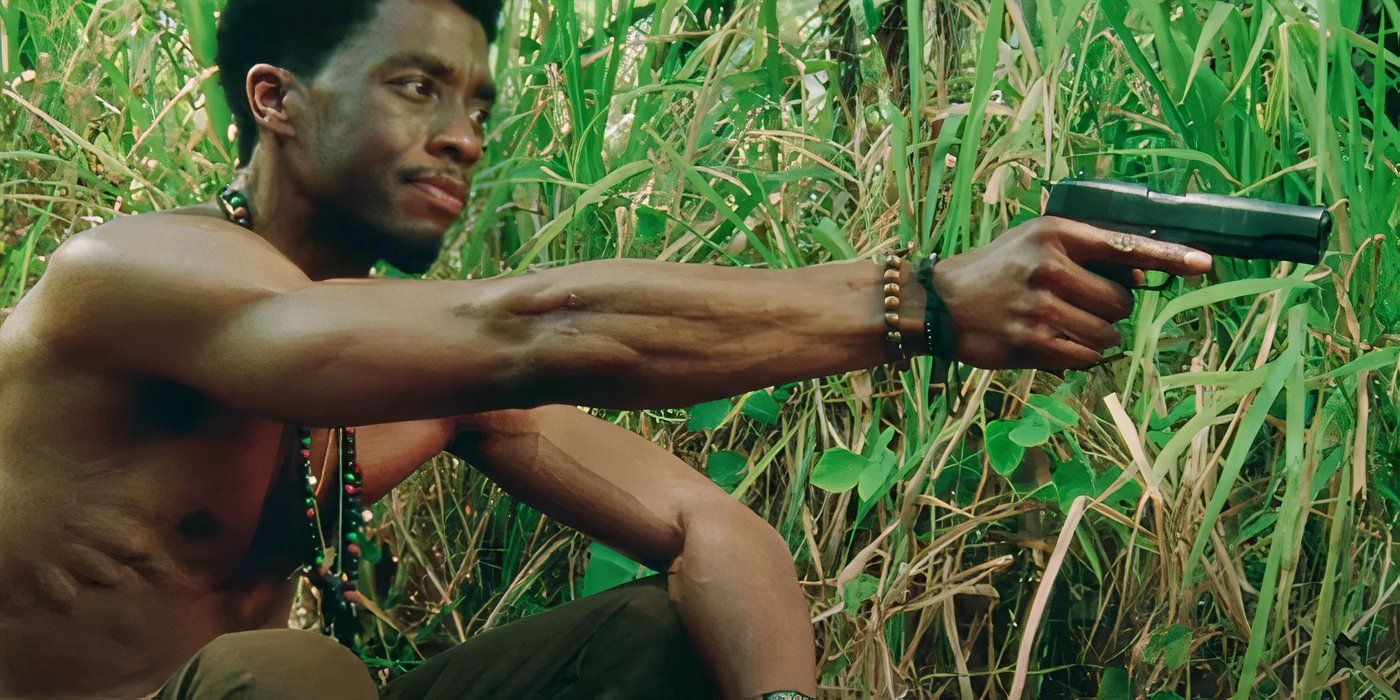 Stormin' Norman crouches against tall grass while holding a pistol in Da 5 Bloods