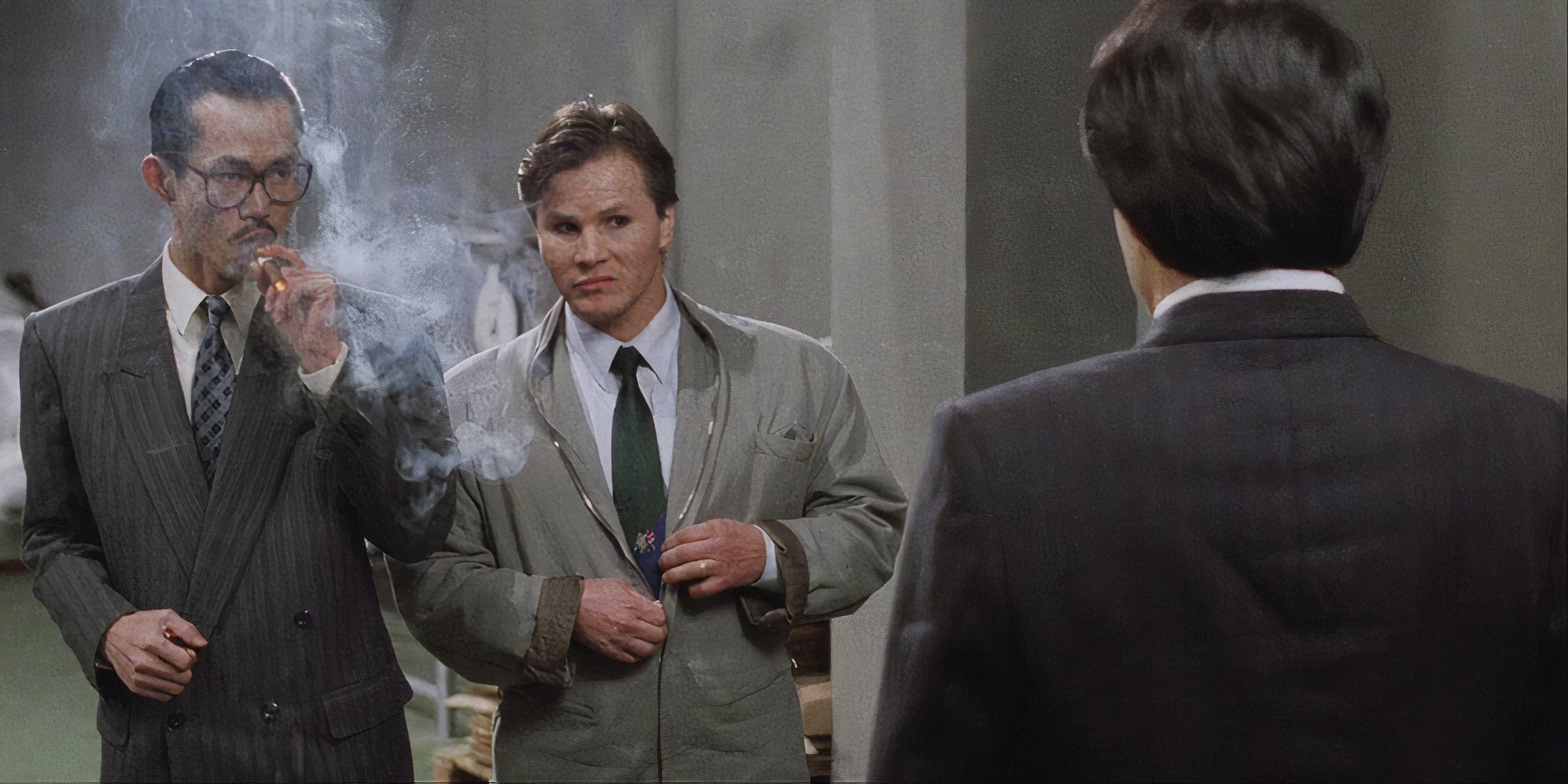 A man smoking a cigar and another man standing next to him talking to Jackie Chan with his back to the camera in Dragons Forever.