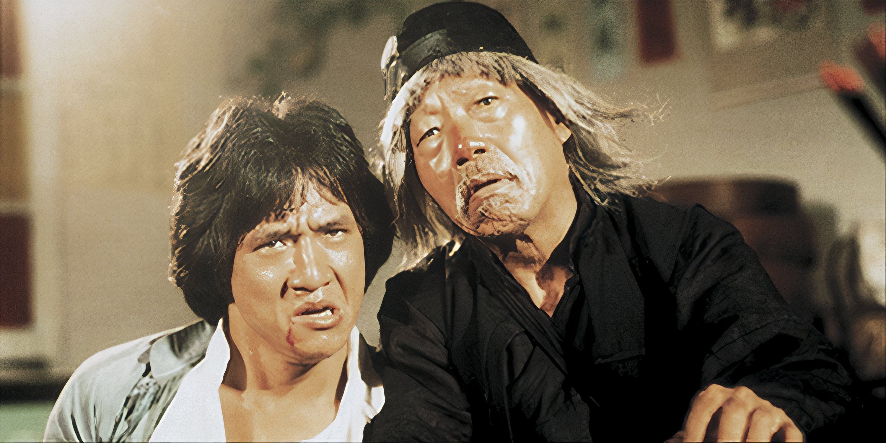 Jackie Chan, with blood on his face, looking confused next to an old man also looking confused in Drunken Master