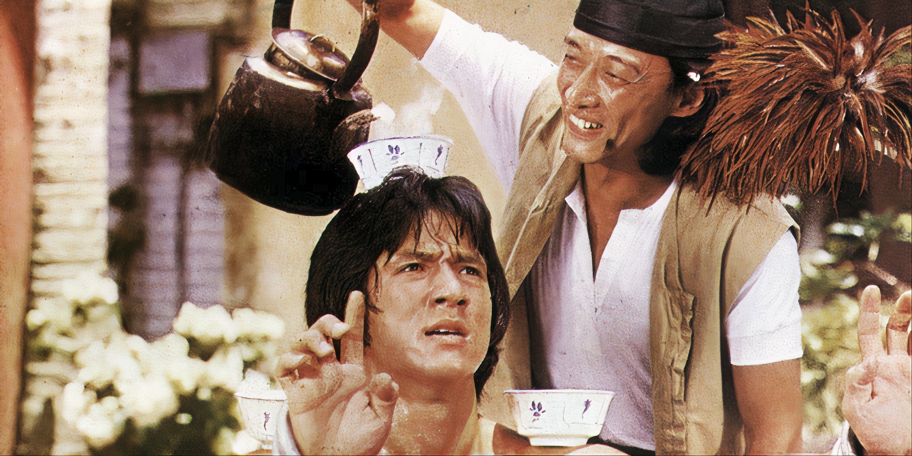 Jackie Chan balances tea cups on his head and shoulders as a man pours tea into them in Drunken Master.