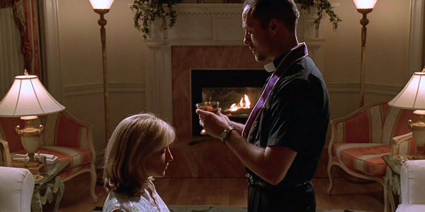 Edie Falco kneels, accepting communion in her living room from her priest friend in The Sopranos' College.