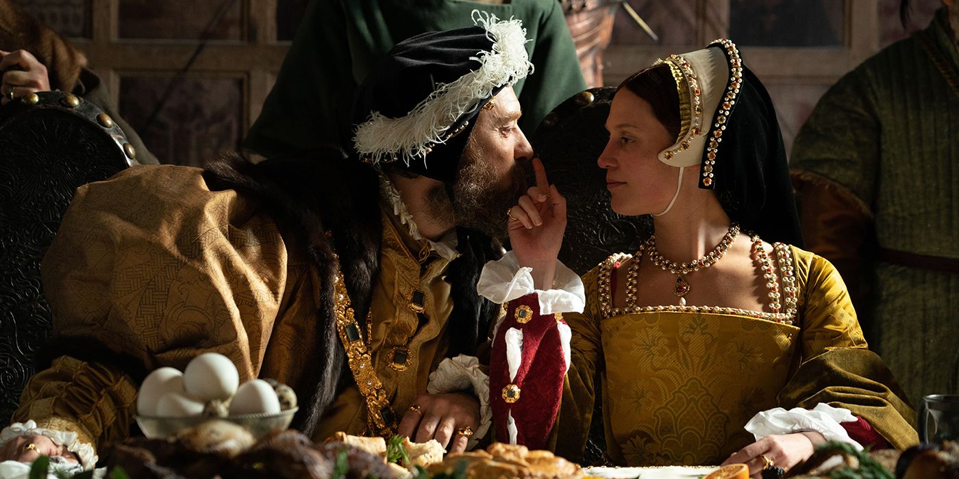 Alicia Vikander touches a finger to Jude Law&rsquo;s nose at a dining hall table in period garb