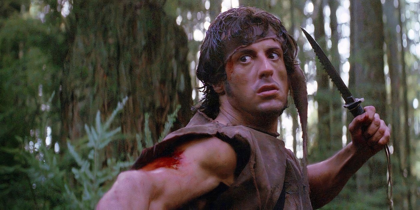 Sylvester Stallone as John Rambo posing with a hunting knife in the forest in 'First Blood.'