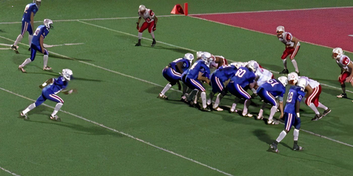 Two football teams in red and blue uniforms line up at the line of scrimmage