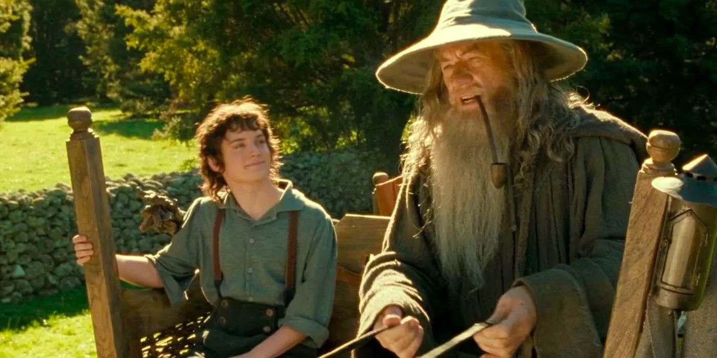 Frodo Baggins (Elijah Wood) and Gandalf the Grey (Ian McKellen) ride a carriage together through the sunny, grassy landscape of the Shire in 'The Lord of the Rings: The Fellowship of the Ring' (2001).