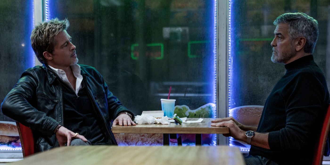 Brad Pitt and George Clooney sitting across from one another at a table in a diner.