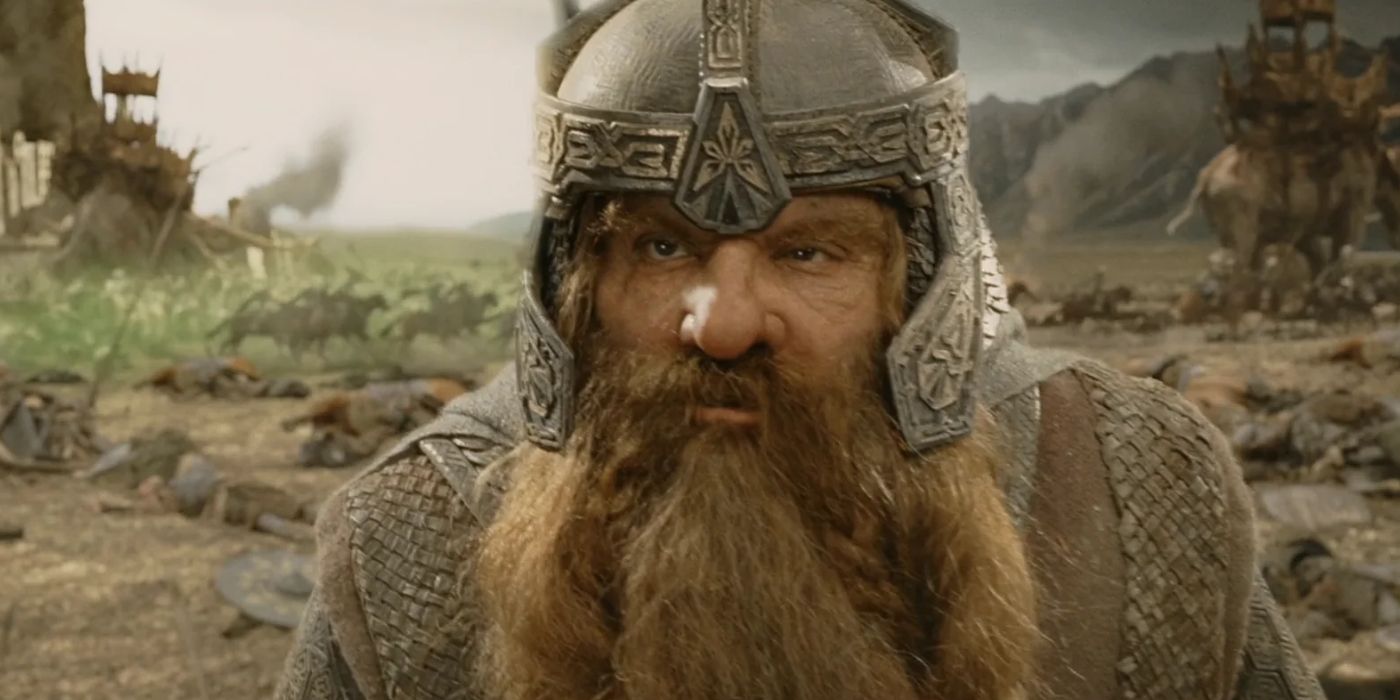 Gimli (John Rhys-Davies) stands on the Pelennor Fields, scowling as he looks at Legolas while the army of the dead attack the orcs in the background in 'The Lord of the Rings: The Return of the King' (2003). 