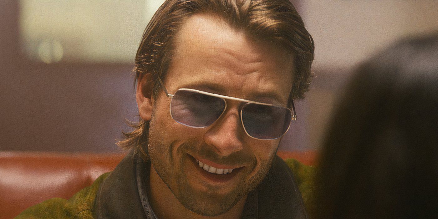 Glen Powell smiling and wearing Aviators while sitting in a diner in Richard Linklater's Hitman