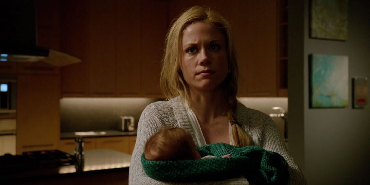Adalind (Claire Coffee) wears a casual white blouse as she holds her baby while standing in a kitchen area in 'Grimm' Season 3, Episode 18 "The Law of Sacrifice" (2014).