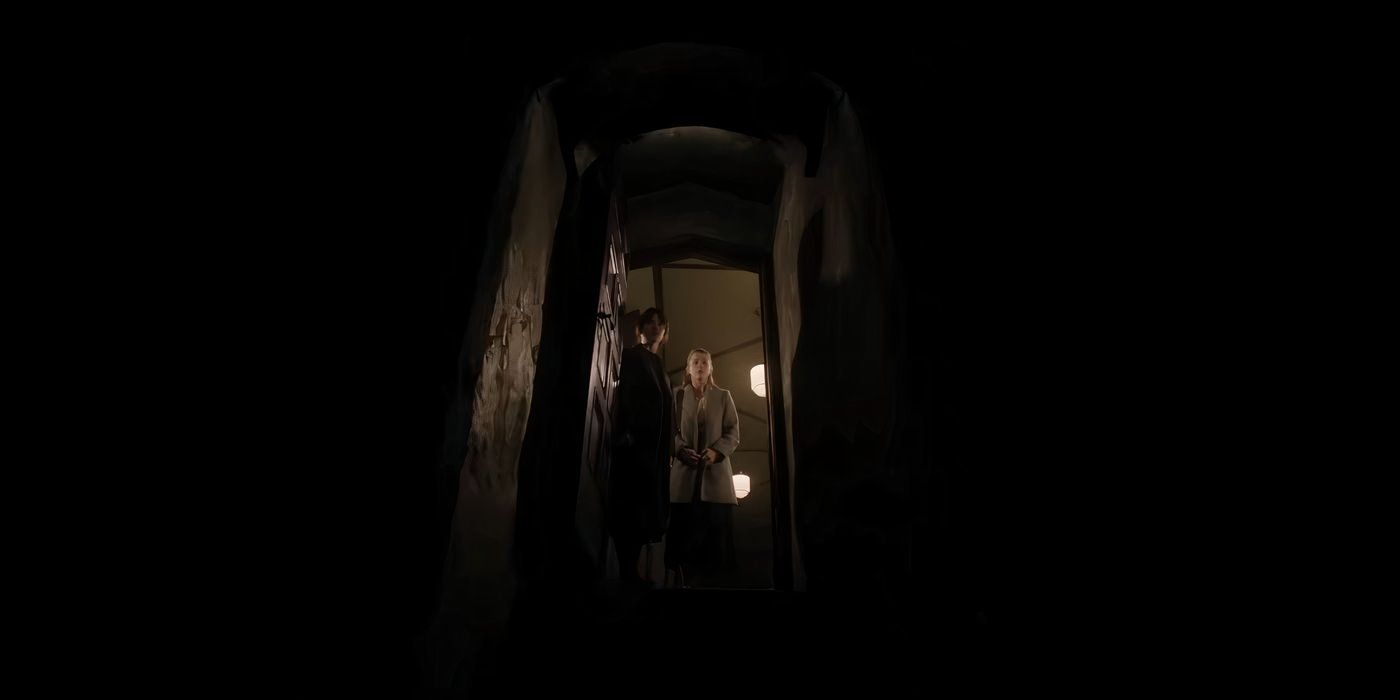 Sophie Thatcher and Chloe East standing in a doorway looking down a dark stairwell in Heretic.