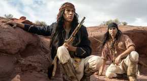 Owen Crow Shoe as Pionsenay holding a gun and standing next to Tatanka Means as Taklishim in Horizon: An American Saga