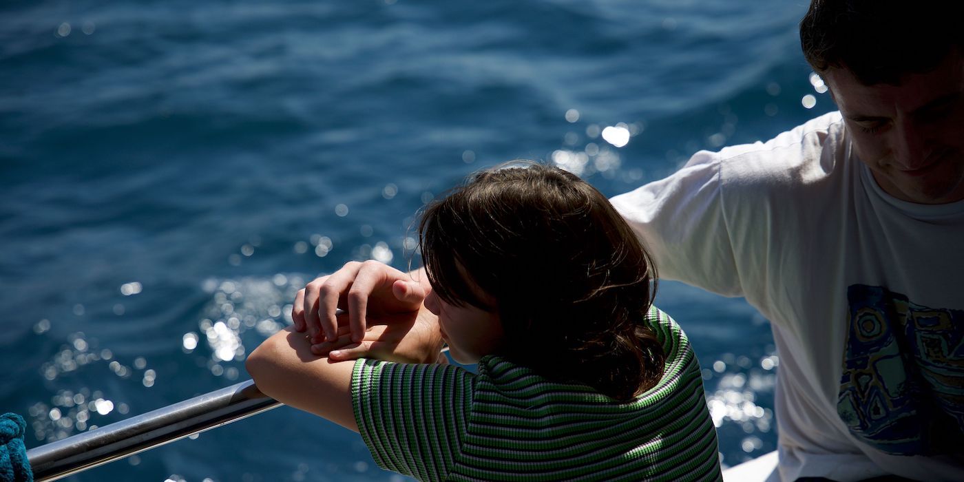 Frankie Corio as Sophie and Paul Mescal as Calum sitting peacefully on a boat together in a still from Aftersun.
