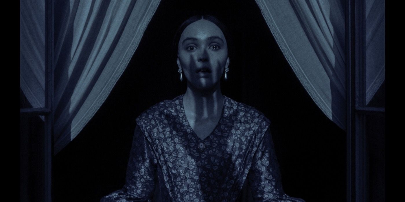 Ellen looking scared with the shadow of a claw on her face in Nosferatu