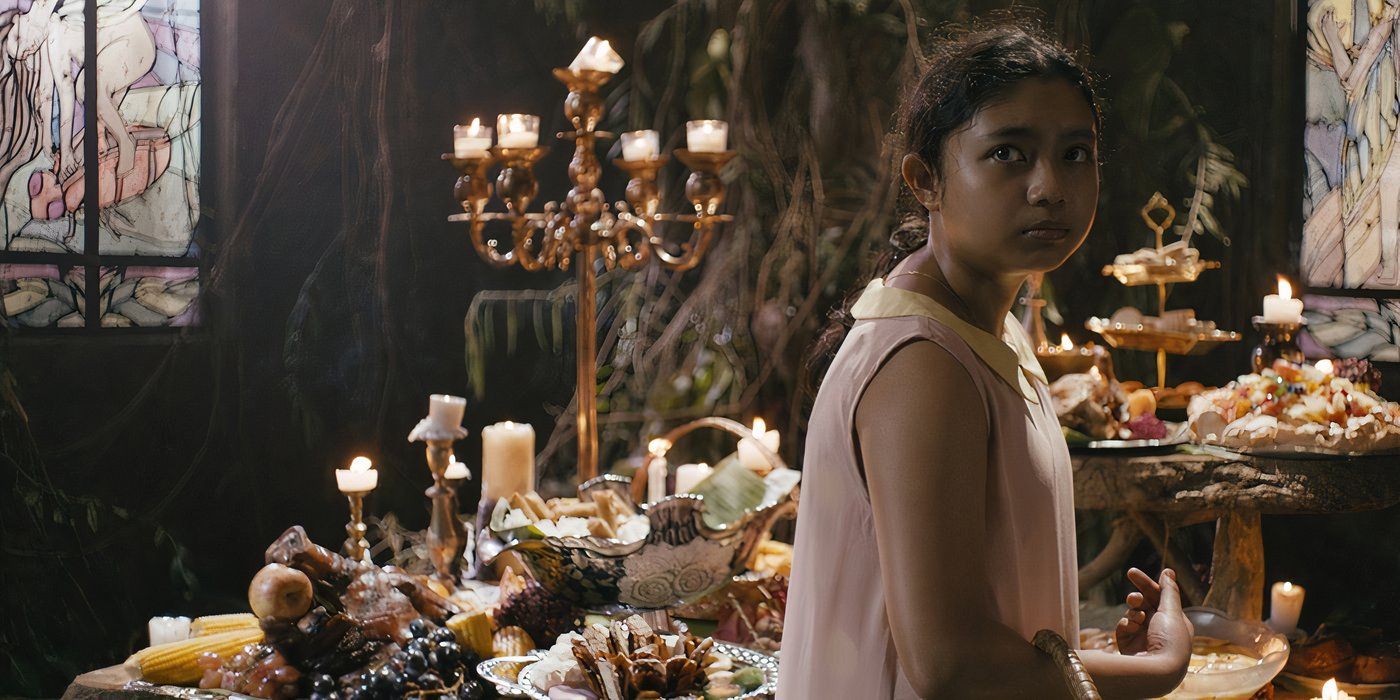 Tala stands in front of a large dinner table loaded with delicious food in in In My Mother's Skin