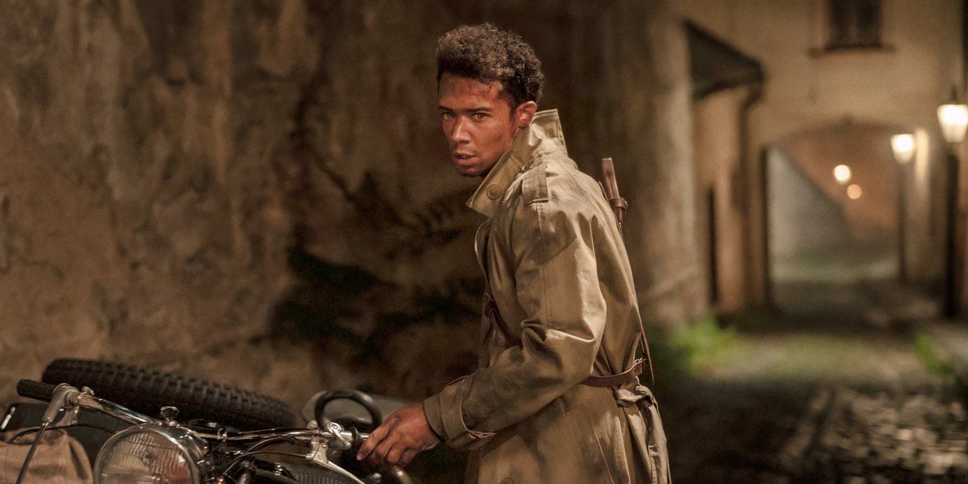 A dirt-covered Louis (Jacob Anderson) wearing a long tan trench coat and holding the handlebars of a motorcycle as he looks off-screen to the left in Interview with the Vampire
