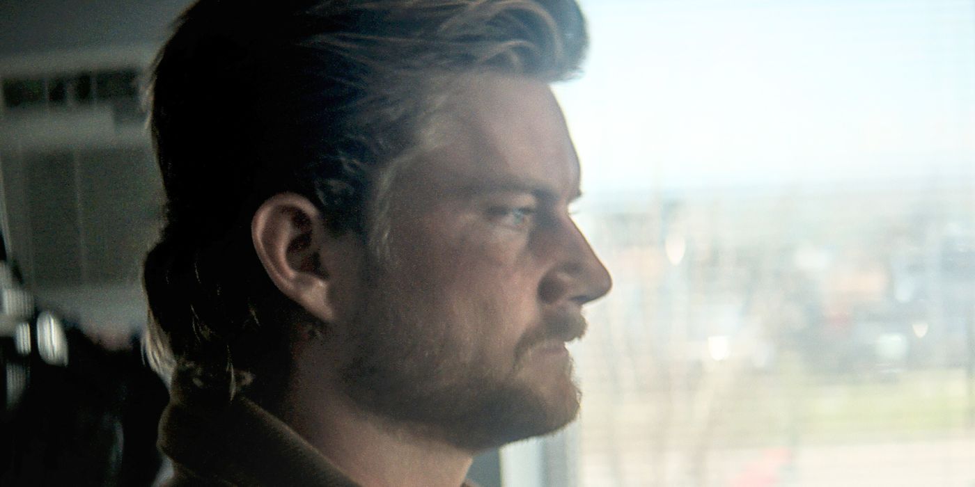 Jake Weary as Elvis, looking at someone while standing in front of a window in Trigger Warning
