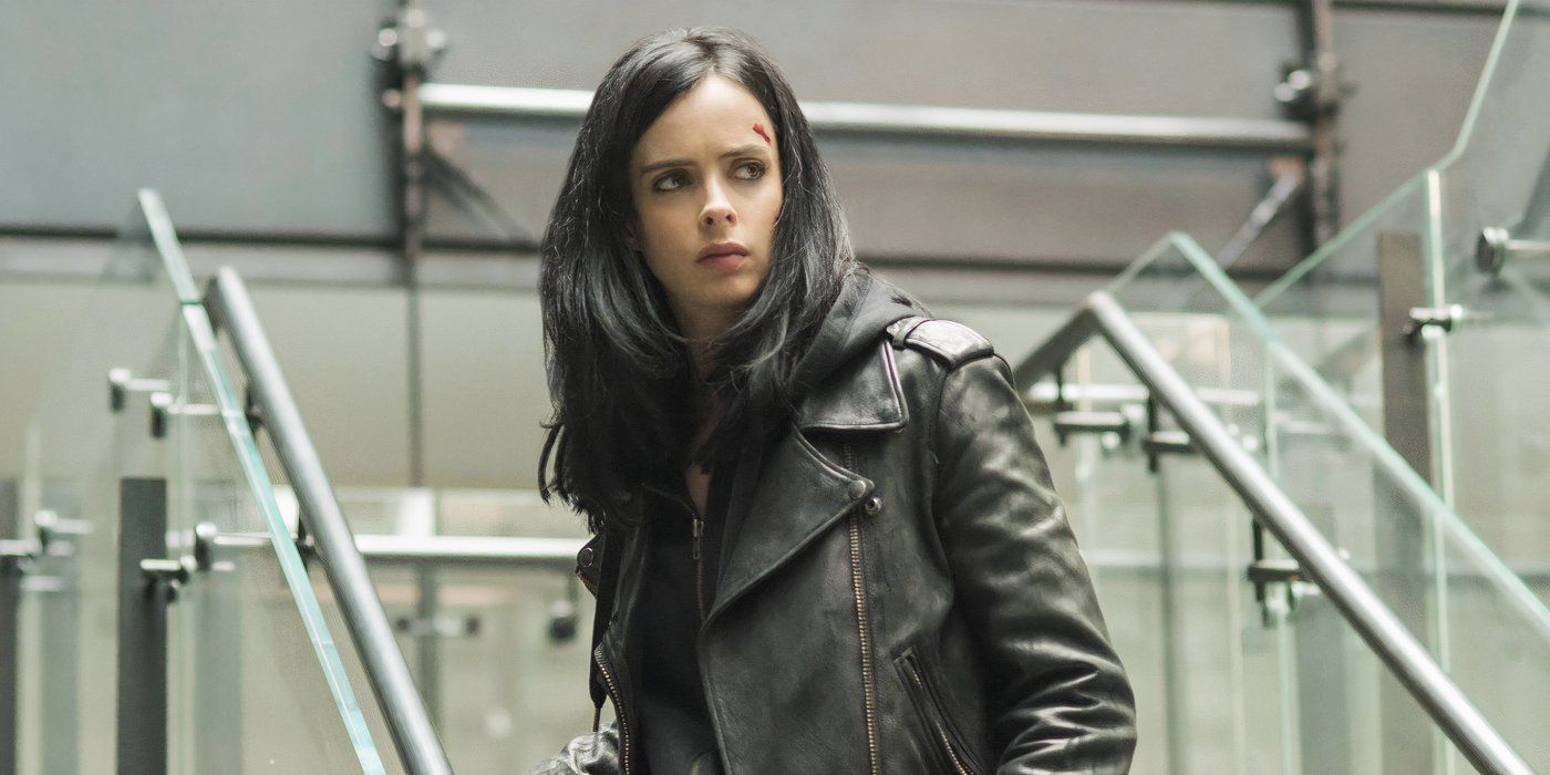 Jessica Jones (Krysten Ritter) parada en las escaleras y mirando ligeramente hacia la derecha.