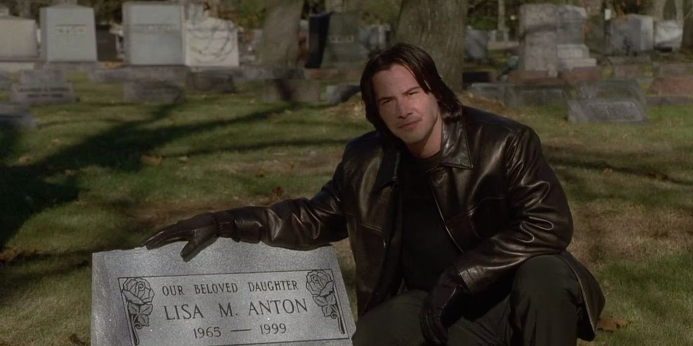 Keanu Reeves as David Allen Griffin sitting by a gravestone in The Watcher (2000)