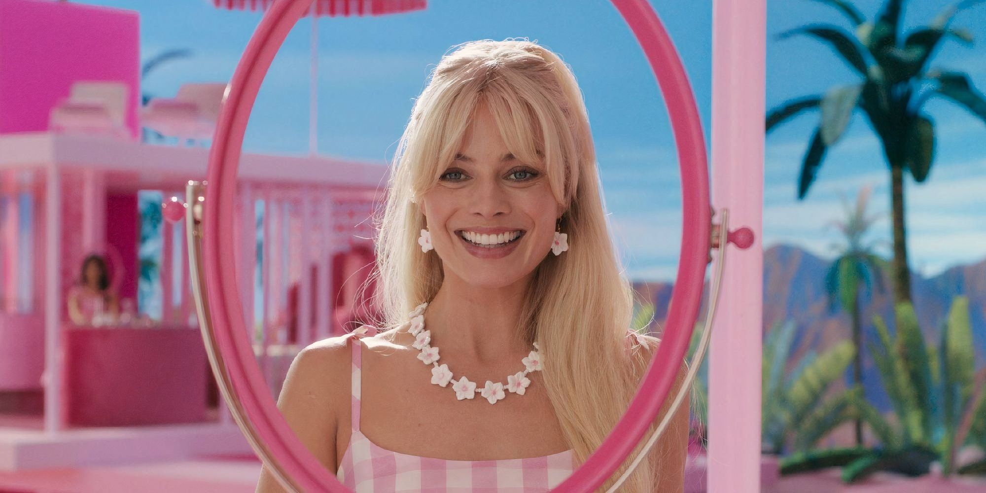 Margot Robbie as Barbie smiling through a mirror in Barbie