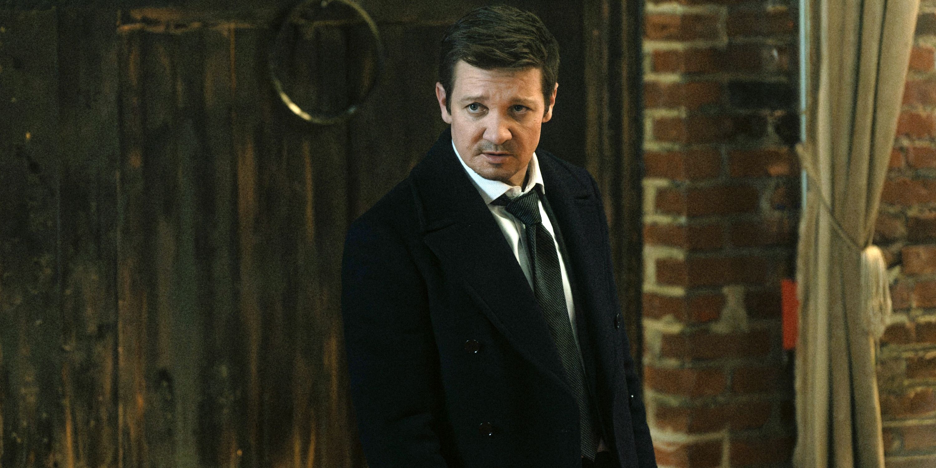 Jeremy Renner as Mike McLusky standing in a suit and tie in Episode 3 of Season 3 of Mayor of Kingstown
