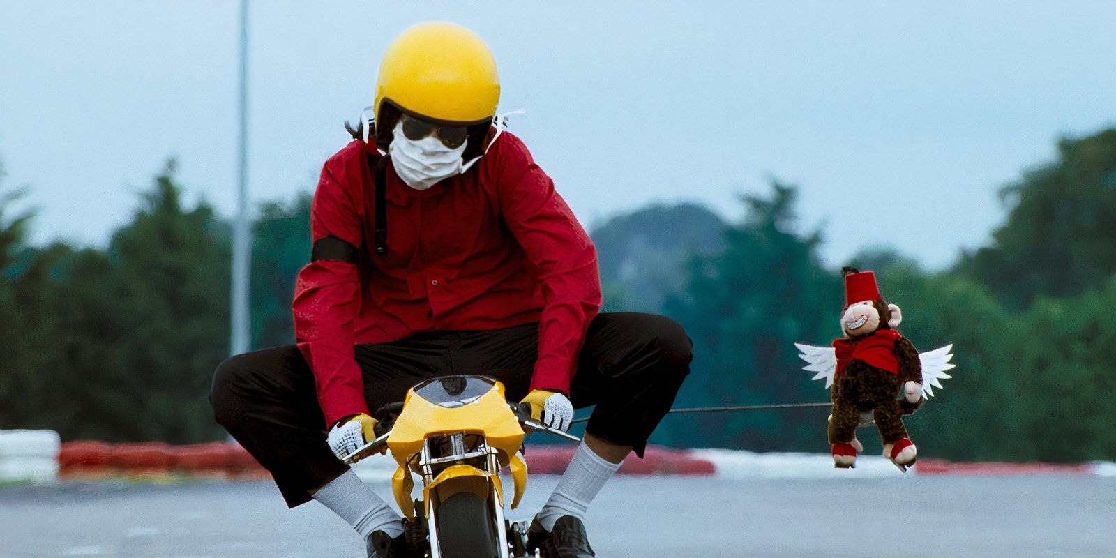 A Michael Jackson impersonator riding a tiny motorized bike, with a helmet and facemask on in Mister Lonely.