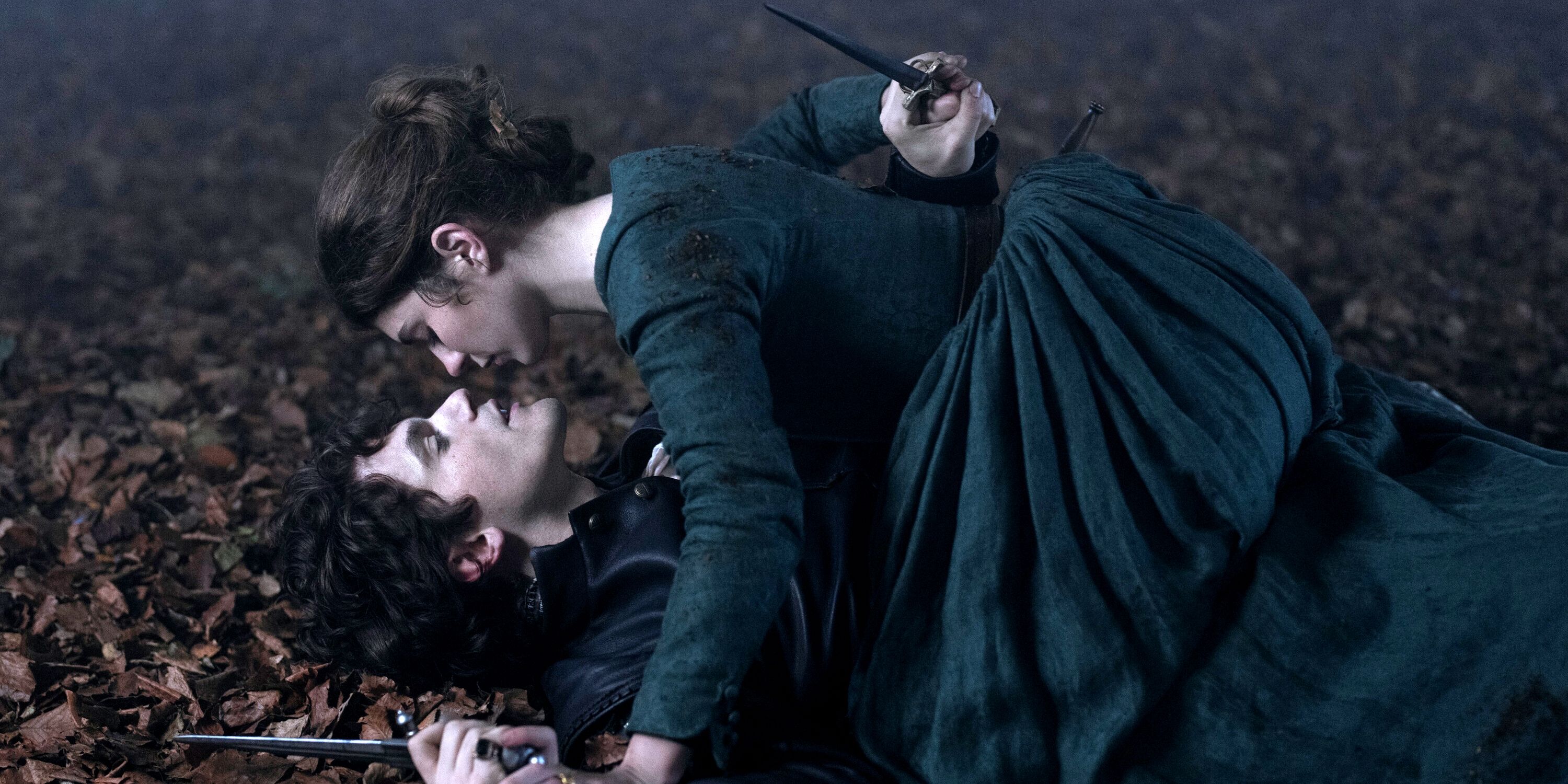Edward Bluemel as Guildford on the ground with Emily Bader as Jane over him in the forest in My Lady Jane