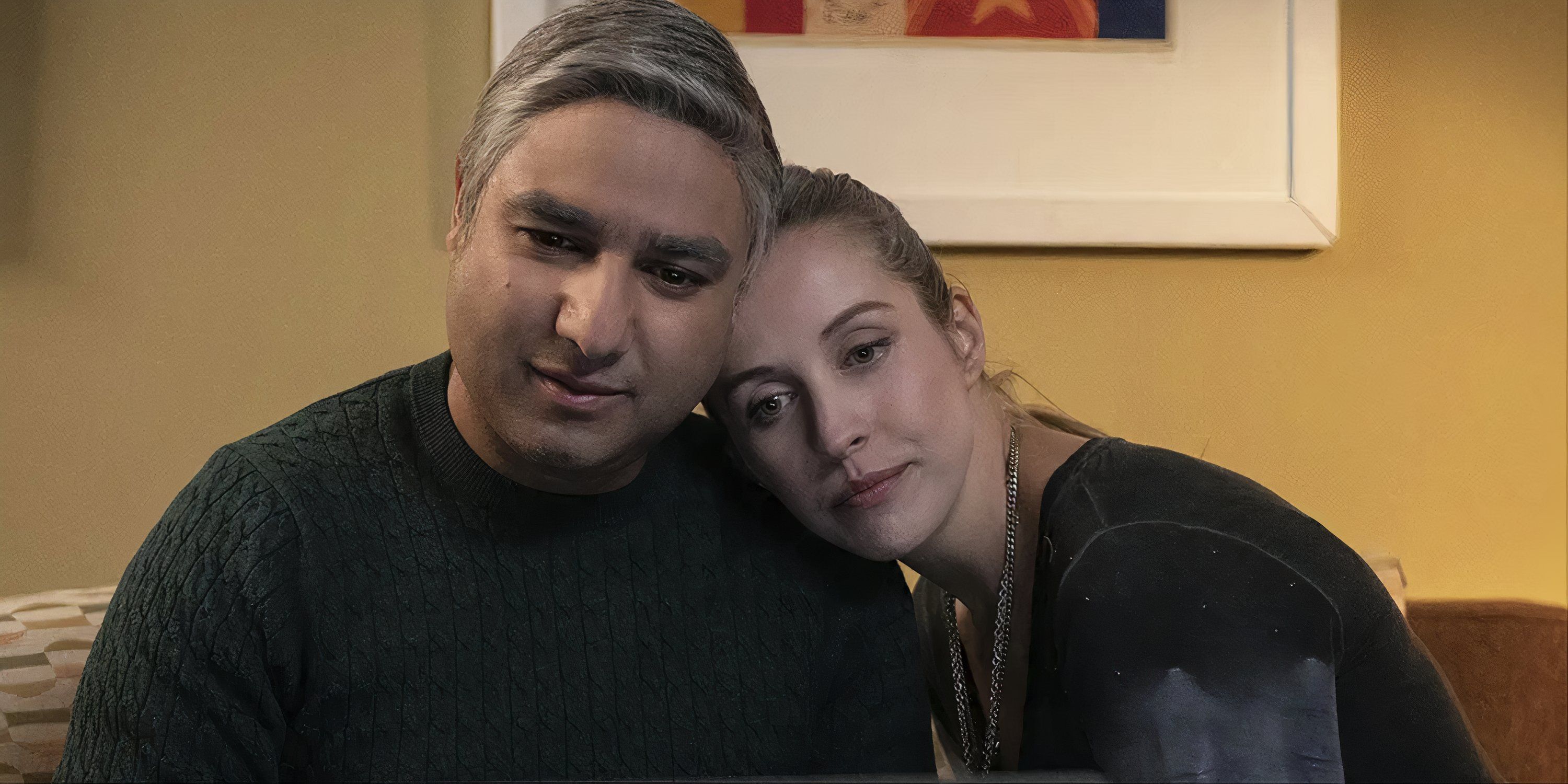 Nick Mohammed as Nate and Edyta Budnik as Jade sitting on a couch holding each other in Ted Lasso