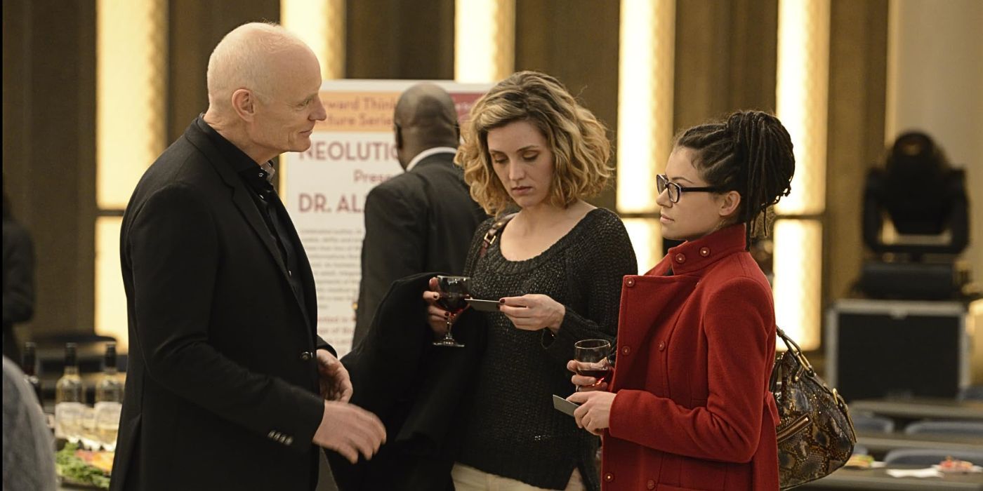 Tatiana Maslany as Cosima and Evelyne Brochu as Delphine talk to Matt Frewer at a lecture in the episode Variations Under Domestication from Orphan Black