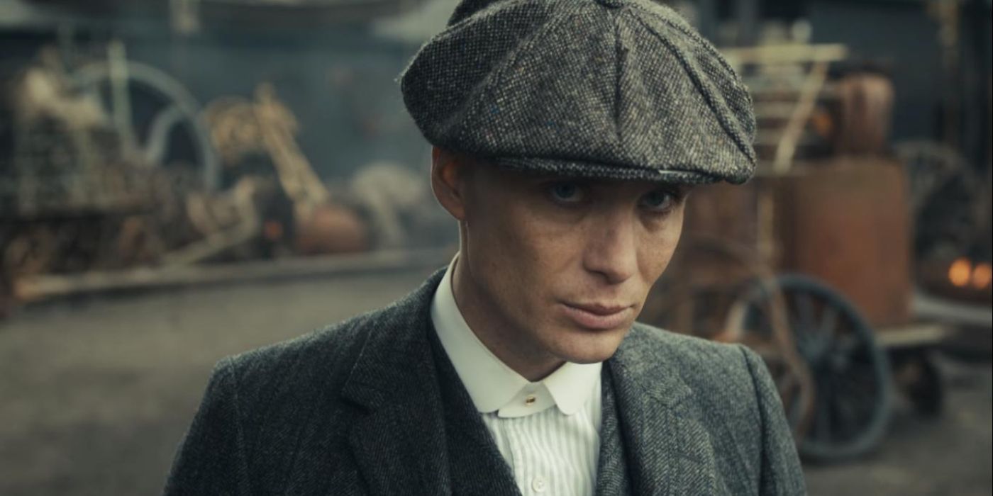 Tommy Shelby (Cillian Murphy) stands in a courtyard wearing his hat in 'Peaky Blinders' Season 1, Episode 1 (2013).