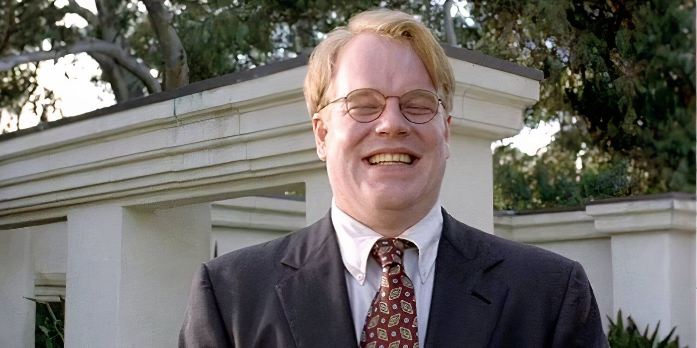 Philip Seymour Hoffman with round glasses and a nice suit laughing with his eyes closed in the Big Lebowski.